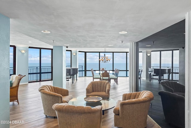 living room featuring an inviting chandelier, a water view, floor to ceiling windows, and hardwood / wood-style flooring