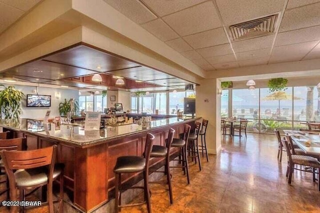 bar featuring a healthy amount of sunlight and a drop ceiling