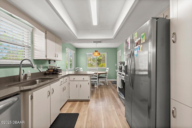 kitchen featuring white cabinetry, sink, stainless steel appliances, and a raised ceiling