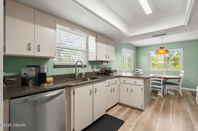 kitchen with sink, white cabinetry, a tray ceiling, dishwasher, and kitchen peninsula