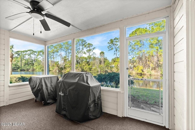 sunroom / solarium featuring a water view and ceiling fan