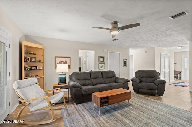 living room with a textured ceiling and light wood-type flooring