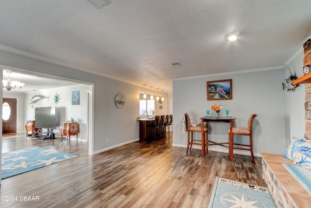 living room with a fireplace, wood-type flooring, ornamental molding, and a textured ceiling