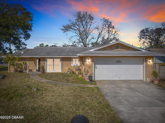 ranch-style house with a garage and a lawn