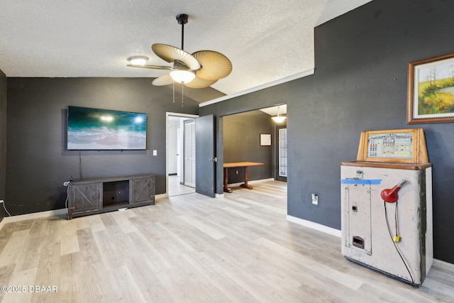 living room featuring ceiling fan, vaulted ceiling, a textured ceiling, and light wood-type flooring