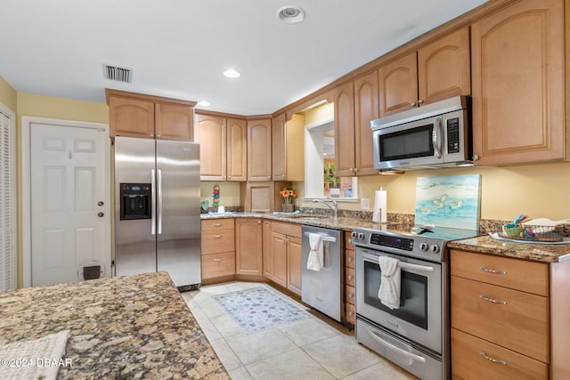 kitchen featuring light tile patterned floors, light stone countertops, sink, and appliances with stainless steel finishes