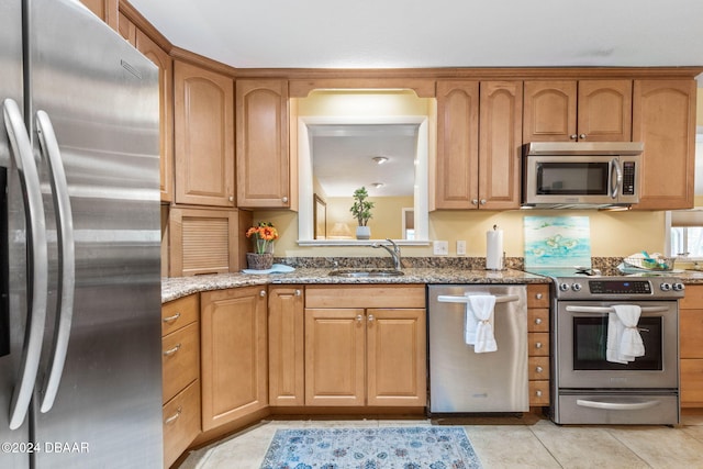 kitchen with light stone countertops, stainless steel appliances, light tile patterned flooring, and sink