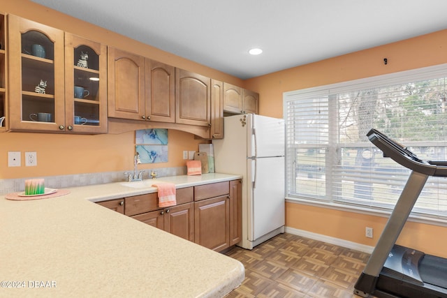 kitchen with dark parquet flooring, white refrigerator, a healthy amount of sunlight, and sink