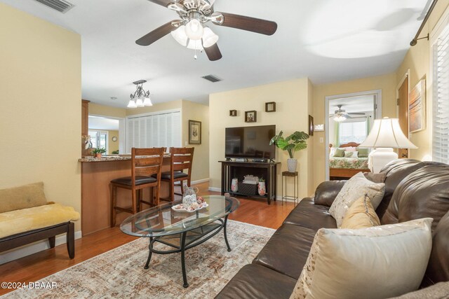 living room featuring plenty of natural light, light hardwood / wood-style floors, and an inviting chandelier