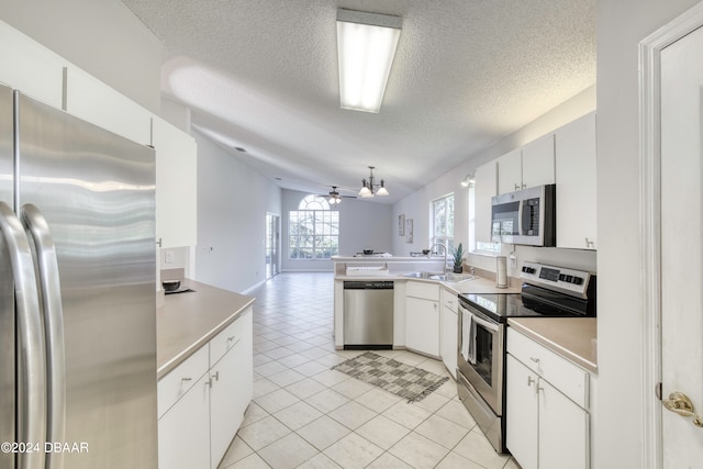 kitchen featuring appliances with stainless steel finishes, ceiling fan, sink, white cabinetry, and hanging light fixtures