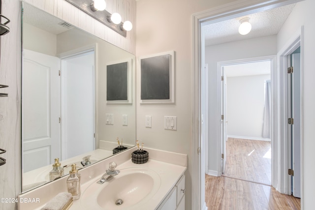 bathroom featuring hardwood / wood-style floors, vanity, and a textured ceiling