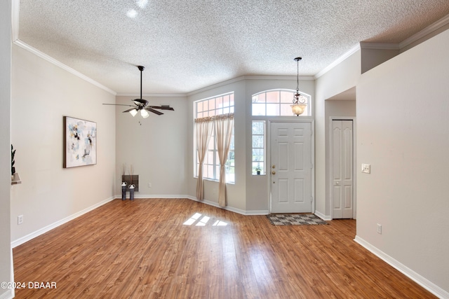 entryway with wood-type flooring, a textured ceiling, ceiling fan, and crown molding