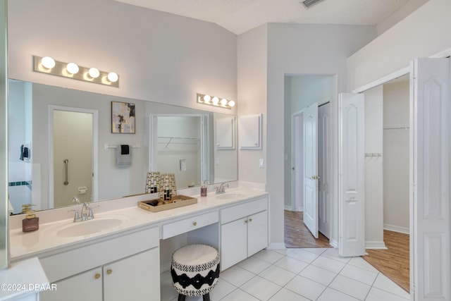 bathroom featuring hardwood / wood-style flooring, vanity, lofted ceiling, and a textured ceiling