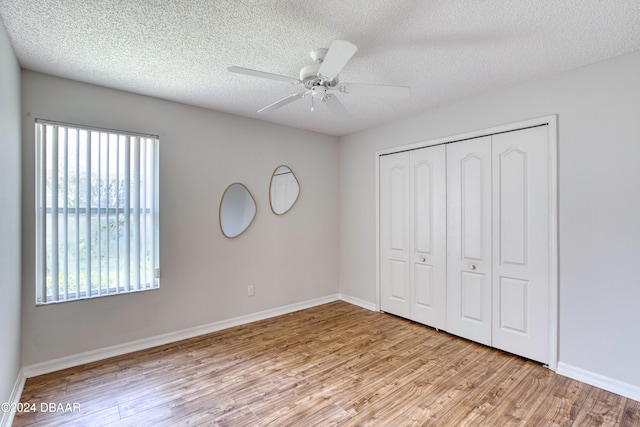 unfurnished bedroom featuring ceiling fan, a closet, light hardwood / wood-style floors, and a textured ceiling