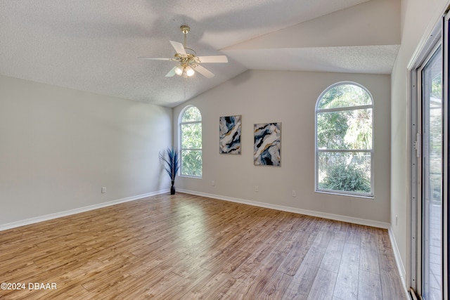 unfurnished room featuring plenty of natural light, light hardwood / wood-style flooring, and vaulted ceiling