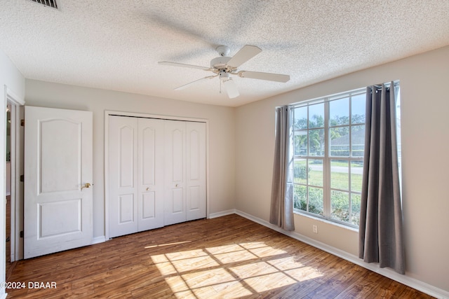 unfurnished bedroom featuring a textured ceiling, light hardwood / wood-style flooring, a closet, and ceiling fan