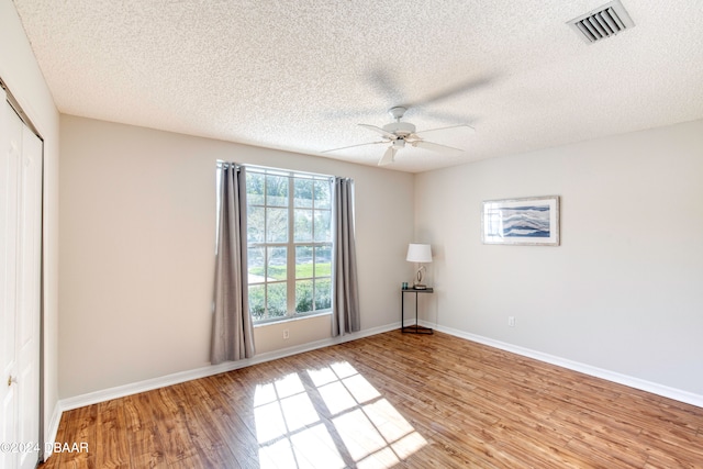 empty room featuring ceiling fan, light wood-type flooring, and a textured ceiling