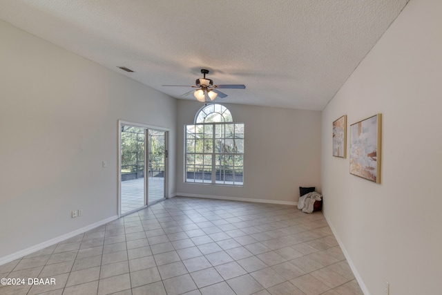 tiled spare room featuring a textured ceiling, ceiling fan, and lofted ceiling