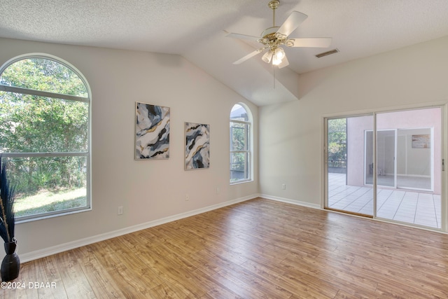 spare room featuring ceiling fan, light wood-type flooring, a textured ceiling, and vaulted ceiling