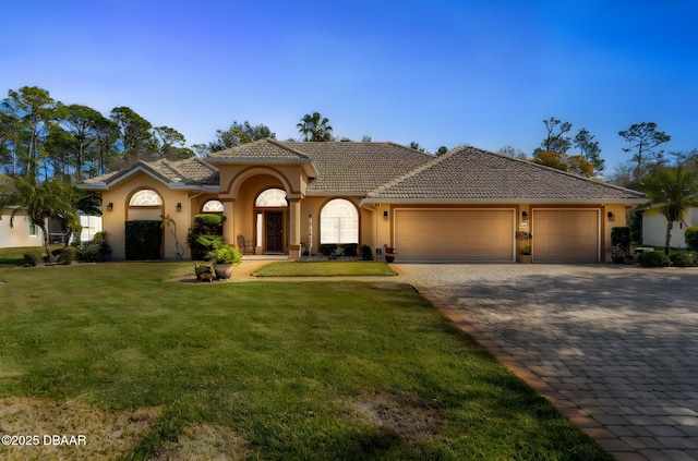 mediterranean / spanish home with a garage and a front lawn