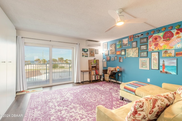 living room featuring a wall mounted air conditioner, ceiling fan, a textured ceiling, and hardwood / wood-style flooring