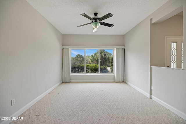 empty room featuring ceiling fan, light colored carpet, and a textured ceiling