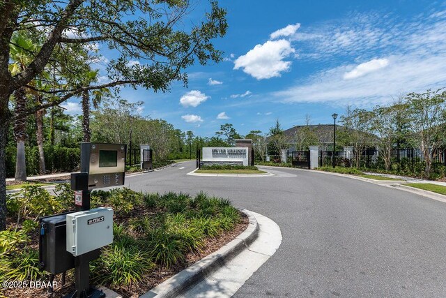 6294 W Fallsgrove Ln, Port Orange, FL 32128 - view of asphalt road featuring curbs, street lighting, a gated entry, and sidewalks