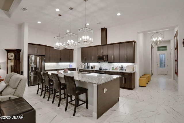 6294 W Fallsgrove Ln, Port Orange, FL 32128 - kitchen with appliances with stainless steel finishes, a chandelier, light marble finish flooring, backsplash, and dark brown cabinetry