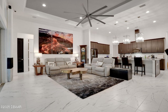 6294 W Fallsgrove Ln, Port Orange, FL 32128 - living room with a high ceiling, a ceiling fan, a chandelier, recessed lighting, and light marble finish flooring