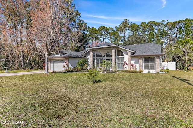 view of front of house with an attached garage, brick siding, fence, driveway, and a front lawn