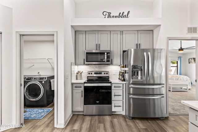 kitchen featuring stainless steel appliances, washer / clothes dryer, light countertops, and visible vents