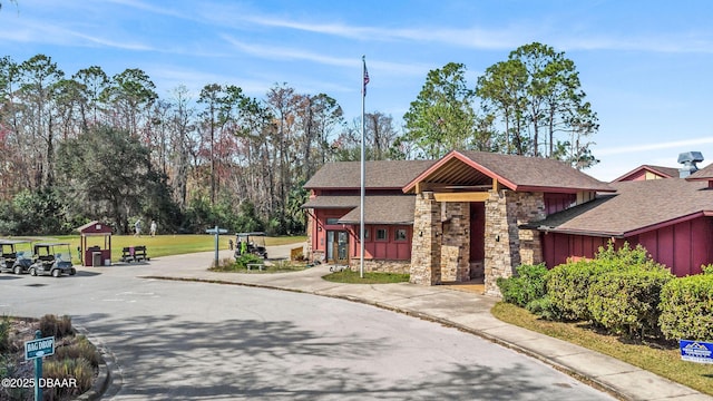 exterior space featuring stone siding, a shingled roof, and board and batten siding