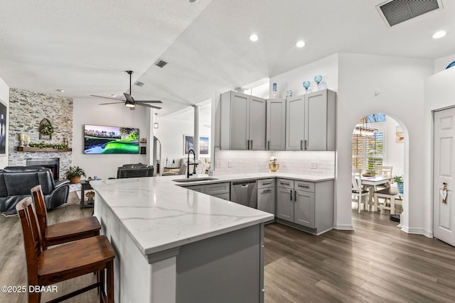 kitchen featuring arched walkways, visible vents, stainless steel dishwasher, open floor plan, and a sink