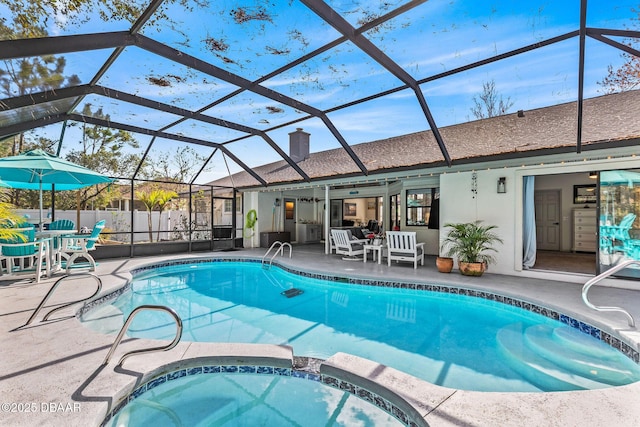 view of pool with a lanai, a pool with connected hot tub, fence, and a patio