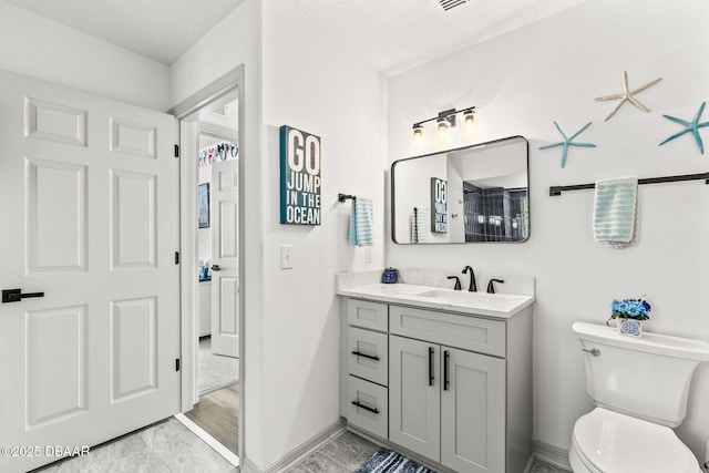 bathroom featuring baseboards, vanity, and toilet