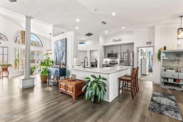 kitchen with gray cabinetry, a peninsula, a sink, appliances with stainless steel finishes, and ornate columns