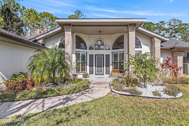 property entrance featuring a yard, brick siding, and stucco siding