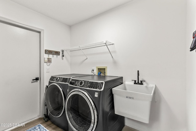 laundry area with laundry area, wood finished floors, a sink, and washer and dryer