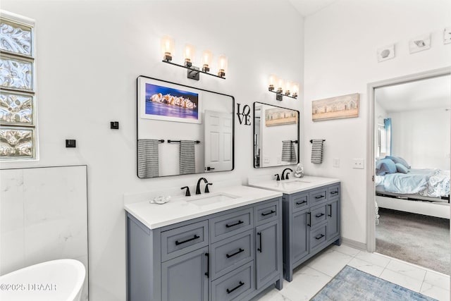 ensuite bathroom with a freestanding tub, vanity, baseboards, marble finish floor, and ensuite bath