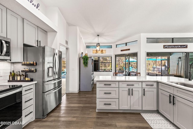 kitchen featuring light countertops, appliances with stainless steel finishes, gray cabinets, a wealth of natural light, and pendant lighting