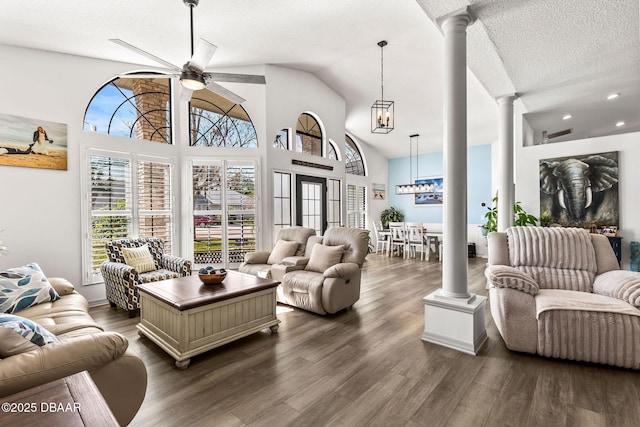 living area featuring dark wood-style floors, ceiling fan, a textured ceiling, and ornate columns