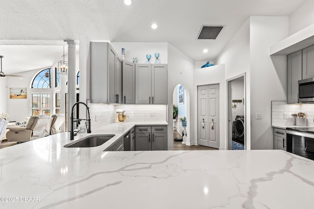 kitchen featuring light stone counters, gray cabinetry, a sink, visible vents, and appliances with stainless steel finishes