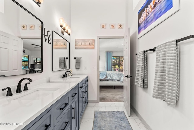 bathroom with baseboards, a sink, ensuite bath, and double vanity