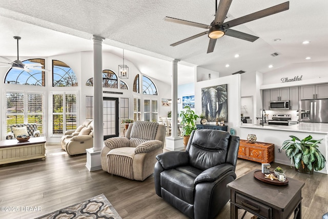 living area featuring ceiling fan, wood finished floors, visible vents, and ornate columns