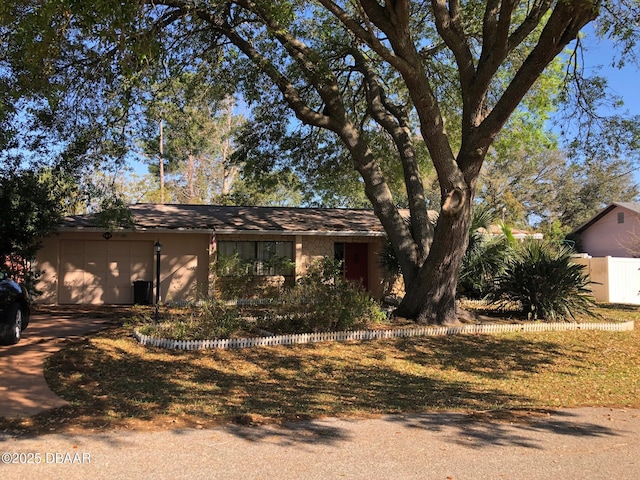 view of front facade with stucco siding, concrete driveway, an attached garage, and fence