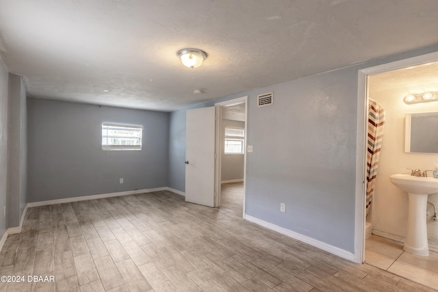 unfurnished room with a textured ceiling, sink, and light hardwood / wood-style flooring