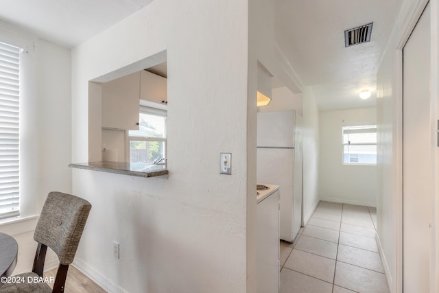 corridor featuring a wealth of natural light and light tile patterned floors