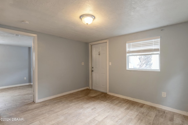 spare room with a textured ceiling and light hardwood / wood-style floors