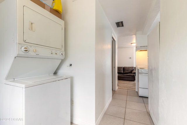 laundry area featuring stacked washing maching and dryer and light tile patterned flooring