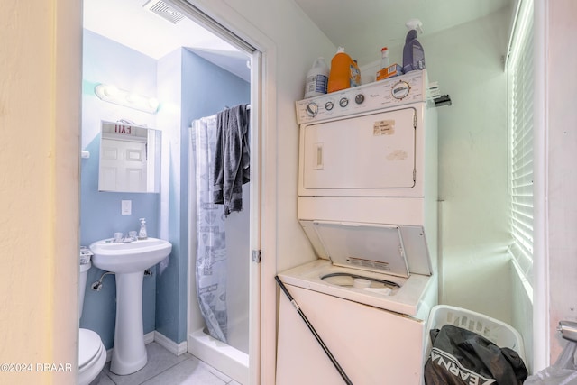 bathroom featuring toilet, stacked washer and clothes dryer, tile patterned flooring, and curtained shower